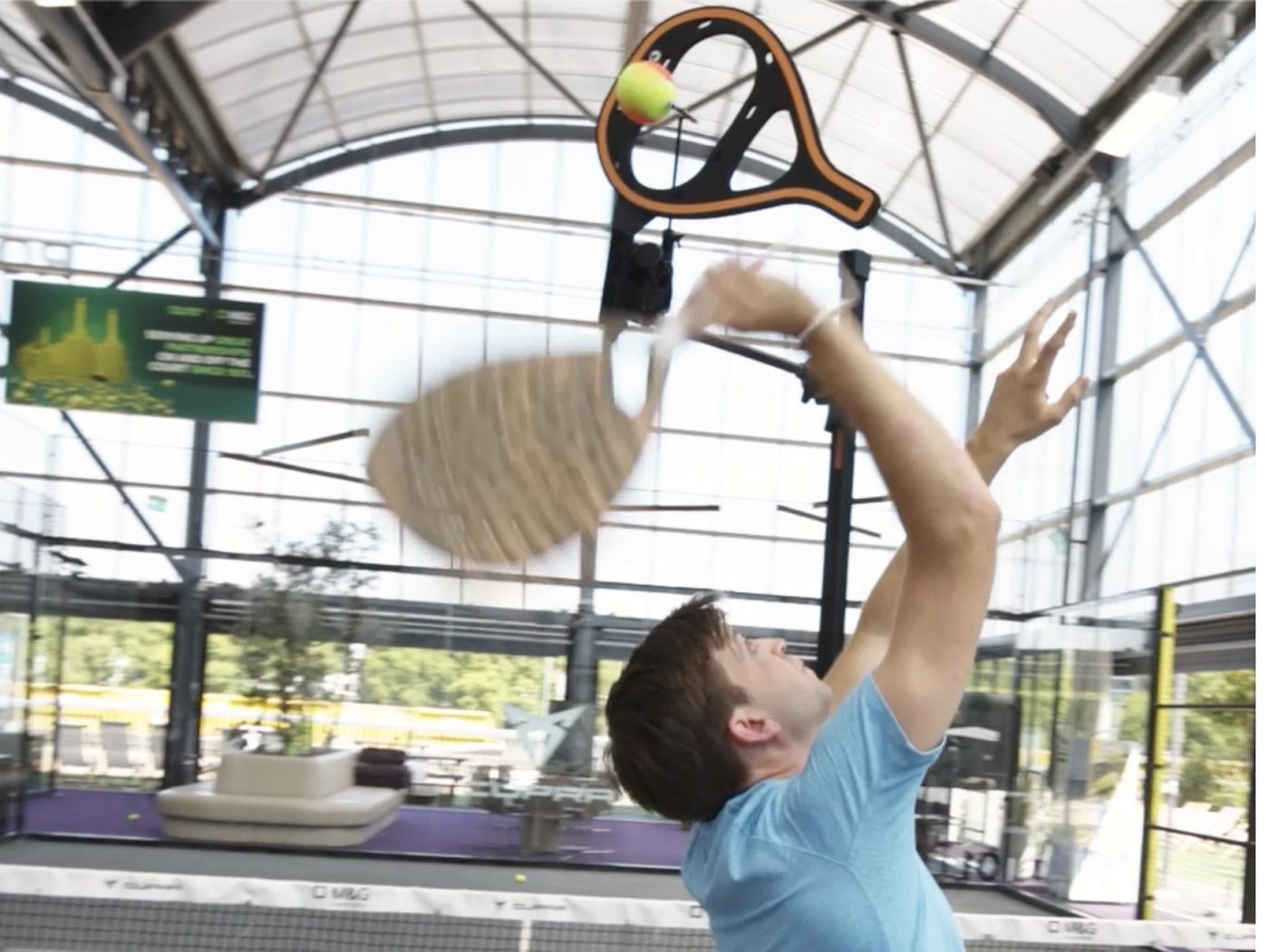 A padel player swinging through the SpinPro screen on an overhead