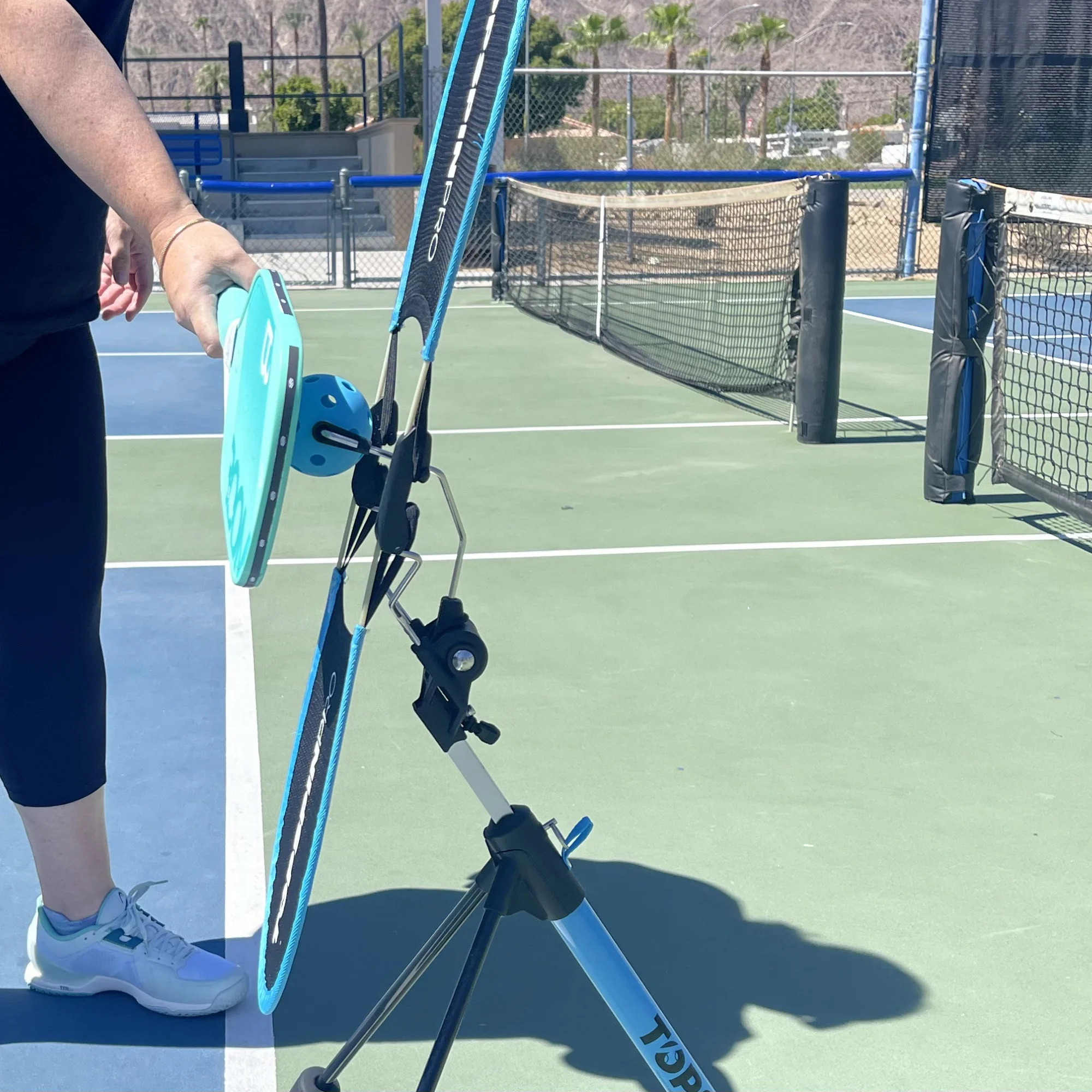 Player brushing up on a pickleball with the TopspinPro Pickleball, side view on an outdoor court